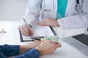 Close-up of a doctor and patient sitting at the desk while physician pointing into laptop computer. Medicine and heal