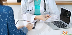 Close-up of a doctor and patient sitting at the desk while physician pointing into laptop computer. Medicine and heal