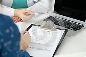 Close-up of a doctor and patient sitting at the desk while physician pointing into laptop computer. Medicine and heal