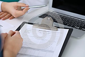 Close up of a doctor and patient sitting at the desk while physician pointing into laptop computer. Medicine and heal