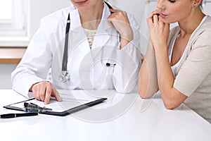 Close up of doctor and patient sitting at the desk while physician pointing into medical form hystory. Medicine a