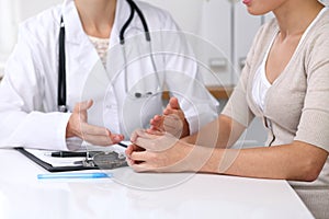 Close up of doctor and patient sitting at the desk while physician pointing into medical form hystory. Medicine a