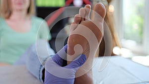 Doctor podiatrist in sterile gloves examining female foot photo