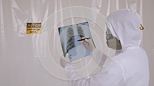 Close-up of a doctor in a protective suit studying an x-ray of a patient's chest