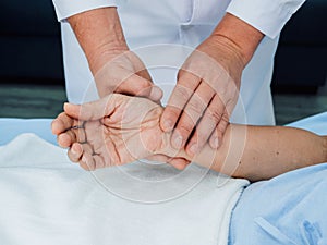 Close up doctor`s hand in white lab coat holding elderly patient`s hand who lying on the bed.