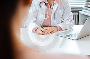 Close-up of doctor taking notes while having appointment with patient