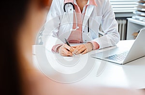 Close-up of doctor taking notes while having appointment with patient photo