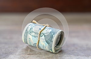 Close up dollar bills roll with rope paste on wooden desktop
