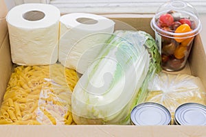 Close up of  donation box. Food supplies  for quarantine isolation period - pasta, vegetables, cans, toilet paper