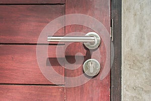 Close up door handle on closed brown wooden door.