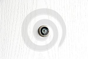 Close up door lens peephole on white wooden texture