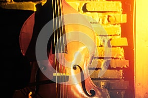 Close-up of double bass on a brick wall background in a club basement, underground jazz music