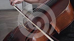Close-up of a double bass with a fiddle-bow, female hand playing on instrument