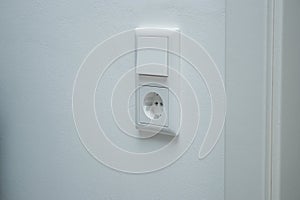 Close up of a double electric light switch and a socket on white wall