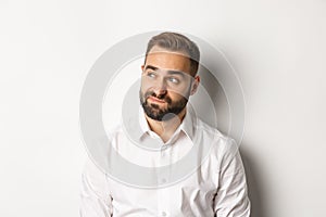 Close-up of doubtful and gloomy man looking left, sighing uncertain, standing over white background