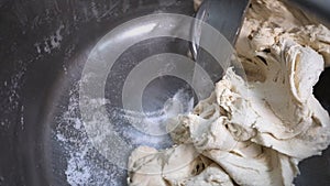 Close-up of dough for baking of baked goods in a professional kneader machine in kitchen of bakery or at the
