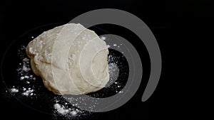 Close-up of dough and flour on a black background. Preparation for pies and rolls. Homemade cakes, cooking