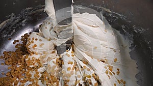 Close-up of dough with raisins in mixer. Stock footage. Delicious industrial pastries prepared for bakery. Large amount