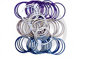 Close up of dozen of white and blue colored bangles along with a dozen  of purple and orange colored bangles isolated on white.