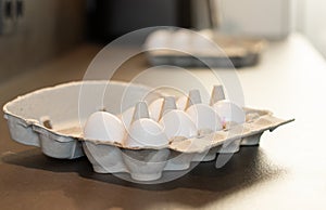 Close up of dozen white eggs in cardboard box on kitchen table