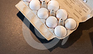 Close up of dozen white eggs in cardboard box on kitchen table