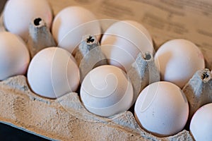 Close up of dozen white eggs in cardboard box on kitchen table