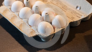 Close up of dozen white eggs in cardboard box on kitchen table