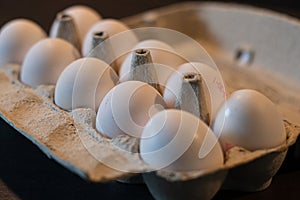 Close up of dozen white eggs in cardboard box on kitchen table