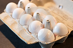 Close up of dozen white eggs in cardboard box on kitchen table