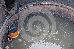 Close-up drain pump in a cesspool filled with contaminated water with feces