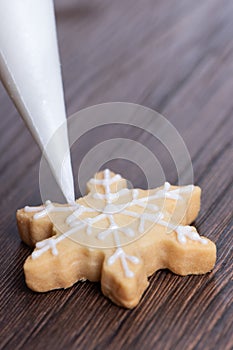 Close up of drawing Christmas snowflake sugar cookie on wooden table background with icing