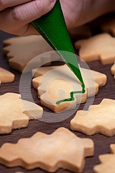 Close up of drawing Christmas tree sugar cookie on wooden table background with icing