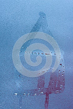 Close-up of drawing of house of condensation on sweaty window pane. Hand draws house on foggy window