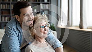 Close up dreamy young man and mature woman hugging