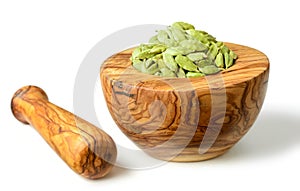 Close up of dried cardamom in the olive wooden mortar, isolated on white