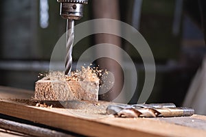 Close-up of the drill in motion when drilling wood in the workshop, freezing motion, sawdust in flight