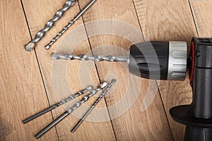 Close up drilling machine, screwdriver with drills on wooden table . Prepared for drilling holes in concrete