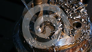 Close-up of drilling machining process in metal part on a lathe, water is pouring on drill, manufacturing