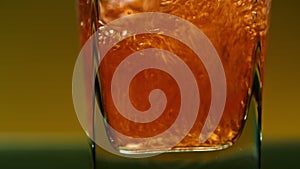 Close-up of drink being poured into transparent glass. Stock clip. Alcoholic drink with bubbles is poured into square