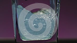 Close-up of drink being poured into transparent glass. Stock clip. Alcoholic drink with bubbles is poured into square