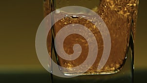 Close-up of drink being poured into transparent glass. Stock clip. Alcoholic drink with bubbles is poured into square