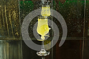 Close up drink shot of a delicious fresh yellow limoncello lemon liqueur cocktail in a transparent glass standing on a table,