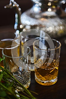 Close-up. Drinking glasses with traditional North African tea and silver teapot on blurred background. Moroccan mint tea