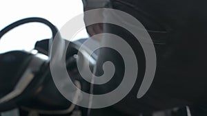 Close up driver door handle of a car is opened by asian man and sitting behind steering wheel.