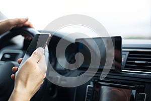 Close-up of driver hand holding smartphone inside car.