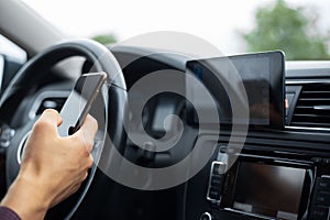 Close-up of driver hand holding smartphone inside car.