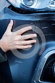Close Up Of Driver Inspecting Damage To Car After Accident