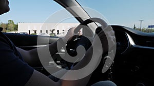 Close-up of the driver's hands holding the steering wheel, driving a car.