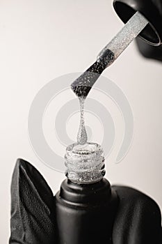 close-up of drop of glitter nail polish dripping from brush into vial