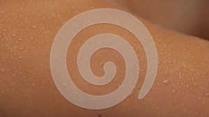 Close-up drops of sweat flowing on female body during enjoying spa sauna. A young woman lies on a couch in the sauna.